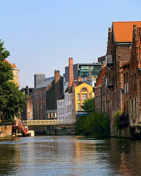 Old factory and residential buildings in Belgian city of Ghent - ancient European center of manufacturing and trade - standing on channel (river)