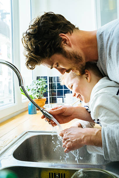 istock Father Washing Sons Hands In Kitchen Sink After Cooking Together 609033970