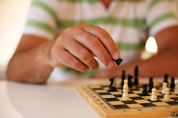uomo anziano che gioca a scacchi, da vicino. - chess positioning strategy individuality foto e immagini stock