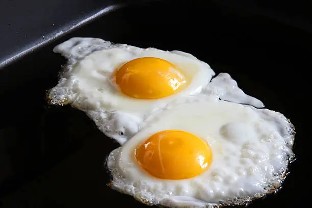 eggs frying sunny side up on frying pan closeup