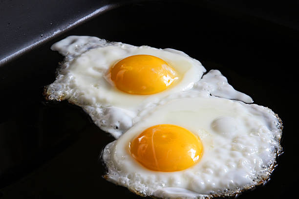 ovos lado ensolarado para cima em close-up frigideira - sunny side up - fotografias e filmes do acervo