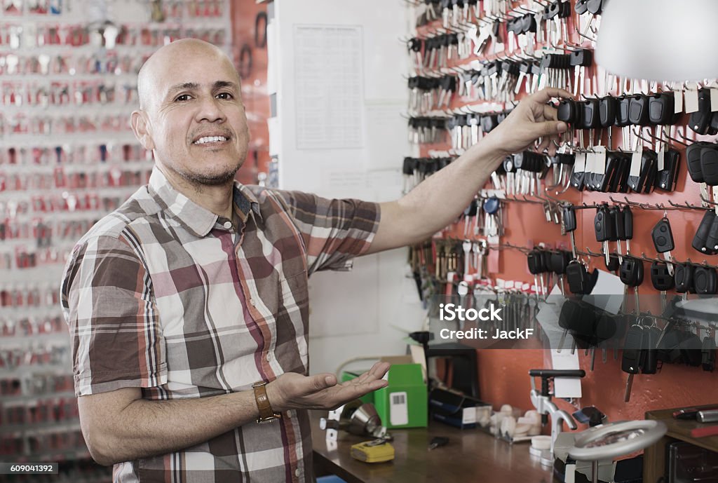 Worker with car keys in locksmith Smiling mature professional workman with assortment of car keys in locksmith Car Stock Photo