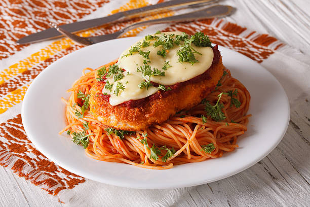 Chicken Parmigiana and pasta with tomatoes close-up Chicken Parmigiana and pasta with tomatoes close-up on a plate on the table. horizontal parmesan stock pictures, royalty-free photos & images