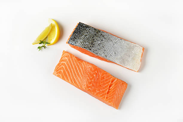 Two raw salmon fillets Two raw salmon fillets and lemon on white background raw food stock pictures, royalty-free photos & images