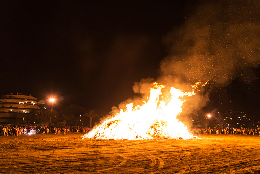 People celebrate St John's Eve (Sant Joan) around a bonfire in a beach of Estartit, Costa Brava, Catalonia, Spain. St John's eve celebration around a bonfire is reminiscent of Midsummer's pagan rituals.