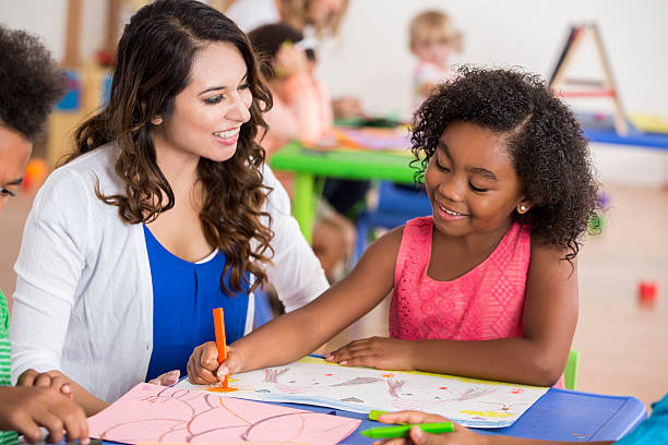 istock Preschool student working on an art project with her teacher 609049626