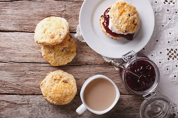 British scones with fruit jam and whipped cream close-up on the table. Horizontal top view