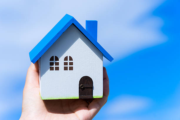 istock Home image, blue house toy in hands 609052322