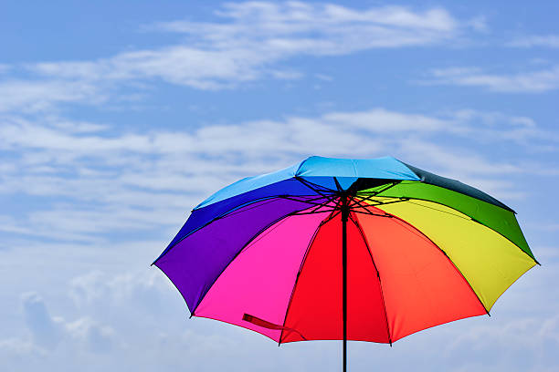 istock Beautiful Rainbow umbrella on bright sky background. 609055782