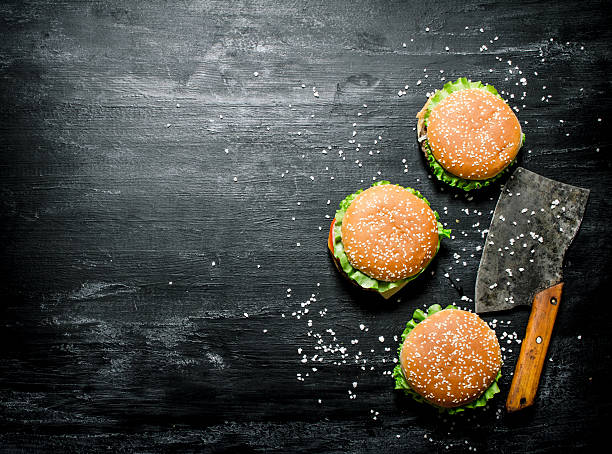 istock Three burgers with a meat ax. On black chalkboard. 609056392