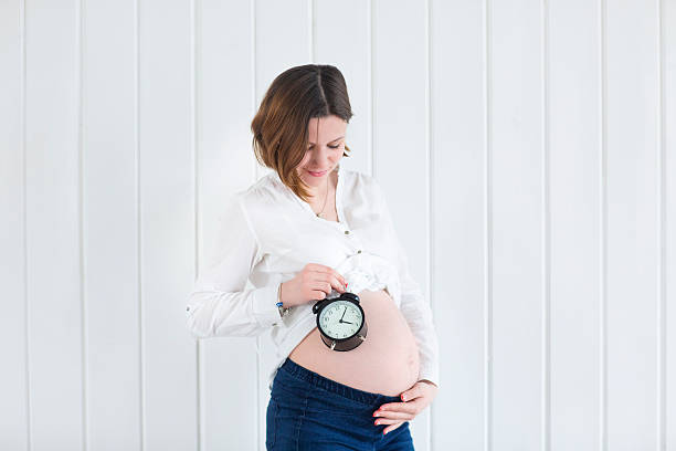 istock Pregnant woman with a alarm clock 609056460