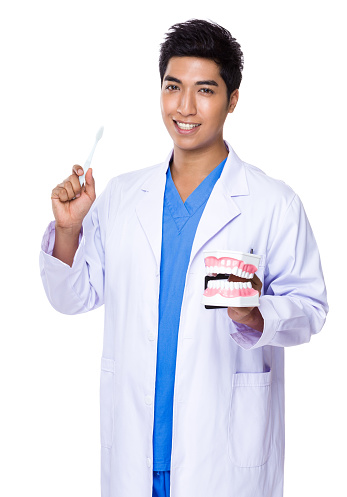 Dentist holding dentures and toothbrush