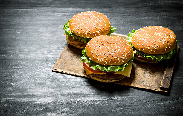 istock Three burgers on a wooden Board. 609057762