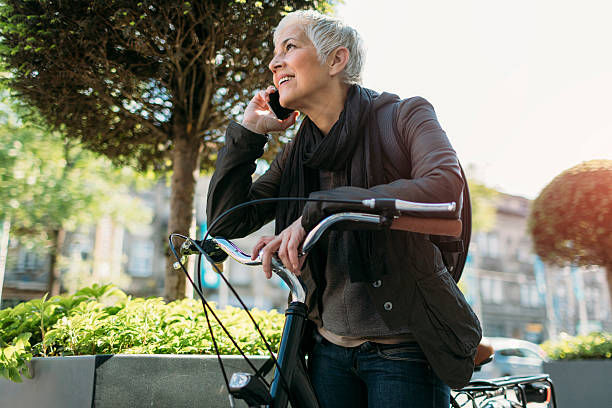 istock Mature Woman Using Phone On Her Bicycle. 609058964