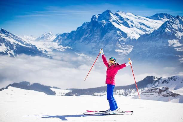 Young active woman skiing in the mountains. Young active woman skiing in mountains. Female skier kid with safety helmet, goggles and poles enjoying sunny winter day in Swiss Alps. Ski race for adults. Winter and snow sport in alpine resort. skiing stock pictures, royalty-free photos & images