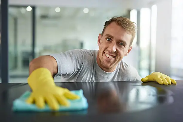 Portrait of a young man wiping off the surfaces in an office