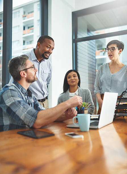 The most successful ideas are formulated as a team Cropped shot of a group of colleagues working together on a laptop in a modern office virtical stock pictures, royalty-free photos & images