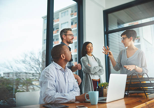 She's bringing some of her bright ideas to the front Cropped shot of a group of colleagues having a discussion in a modern office business meeting stock pictures, royalty-free photos & images