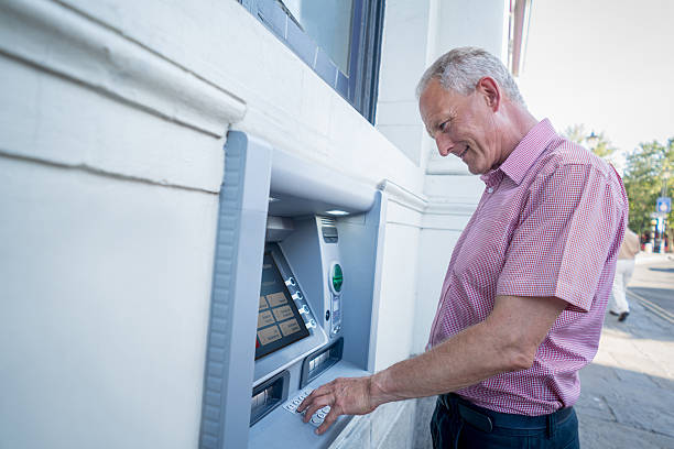 man withdrawing money from an atm - bank of england 個照片及圖片檔
