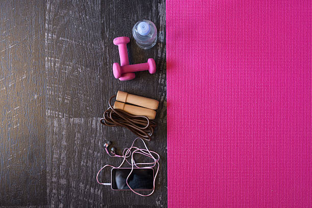 Woman fitness equipment and pink yoga mat on wooden background stock photo