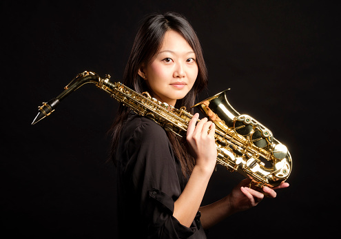 A young Japanese woman holding a saxophone.