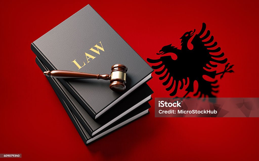 Gavel and Law Books on Albanian Flag: Albanian Justice Concept Wooden gavel and a leather covered law books on Albanian flag.  The book and the gavel are lit by a spotlight from the upper left corner and casting soft shadows on background. Nicely textured. Activity Stock Photo