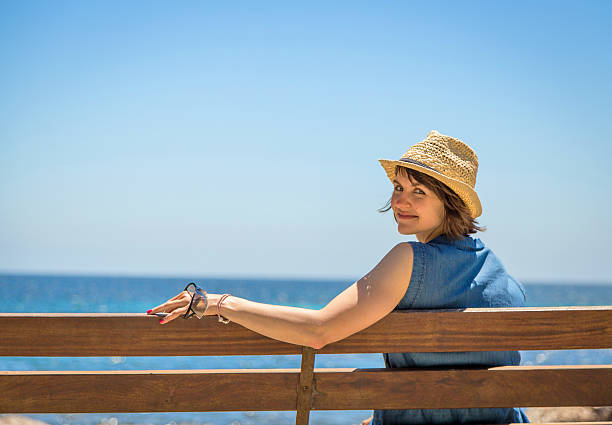 Young woman sitting alone on a bench near the sea stock photo