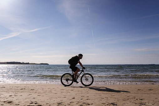 Sola beach, Rogaland, Norway - September 19, 2016. Man is riding a bicycle along North sea  on Sola beach near Sola airport, Norway.