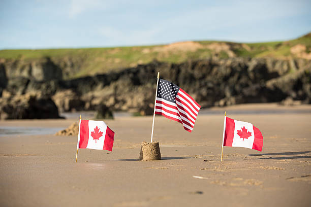 istock Two Canadian Flags with a USA  flag on a beach 609081010