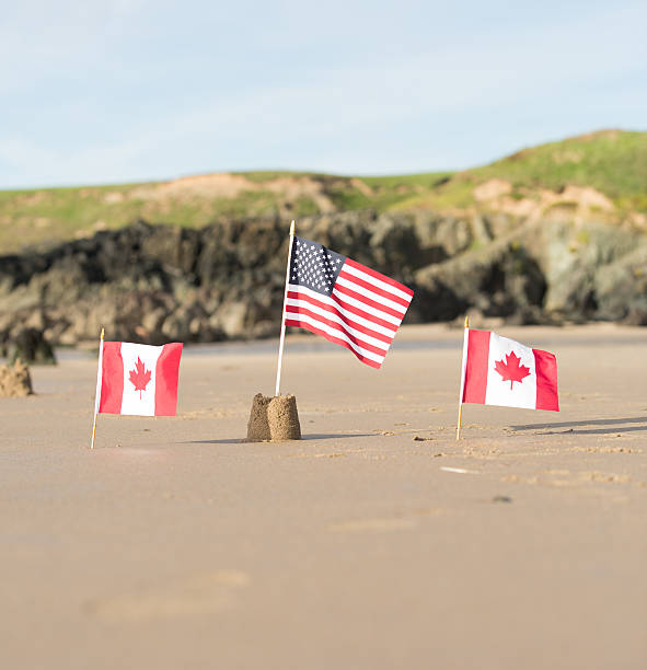 istock Two Canadian Flags with a USA  flag on a beach 609081098