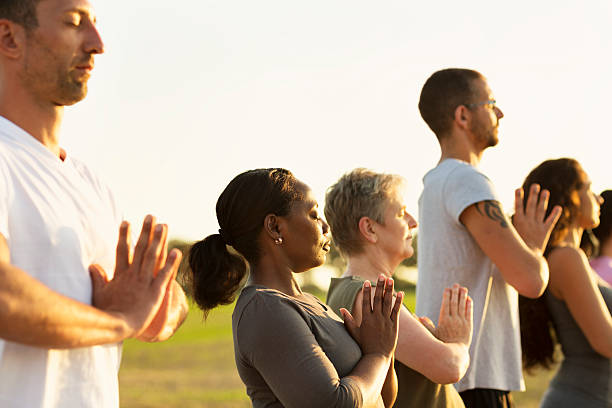 istock Group exercising Yoga outdoors at sunset 609081158