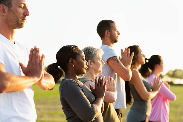 istock Group exercising Yoga outdoors at sunset 609082088