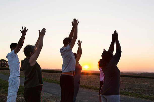 istock Group exercising Yoga outdoors at sunset 609084714