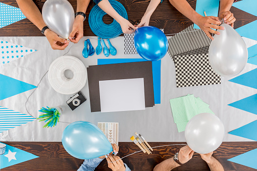 Group of friends sitting together at the table and preparing the party decorations