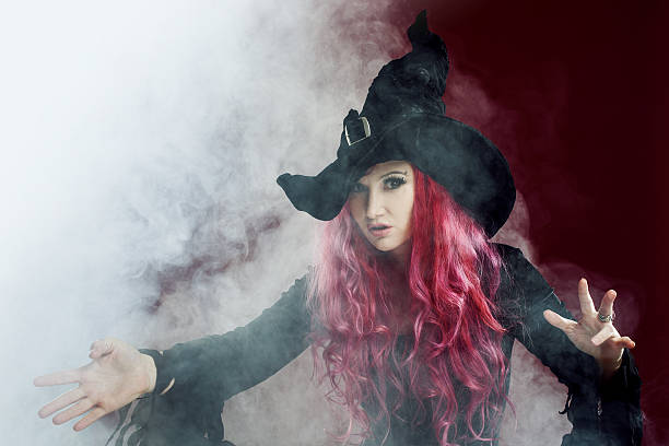 istock Attractive woman in witches hat with red hair performs magic 609087768