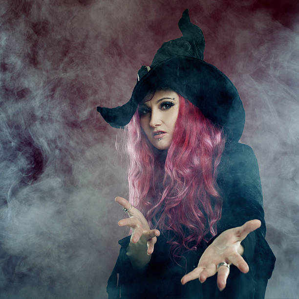 istock Attractive woman in witches hat with red hair performs magic 609088038