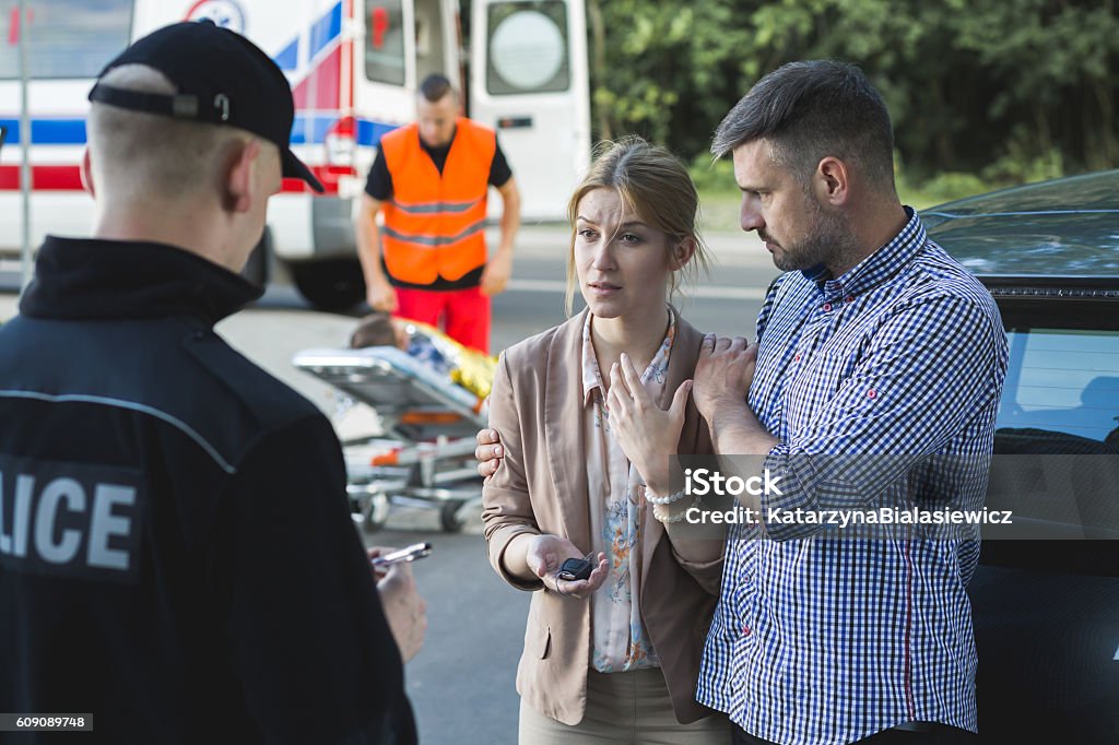 Please, try to calm dawn Bystanders describing the scene of an accident to the police officer Car Accident Stock Photo