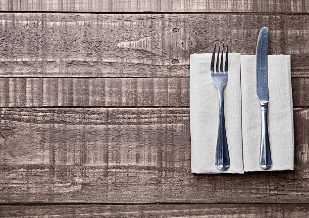 istock Knife and fork inside kitchen towel on wooden board 609091422