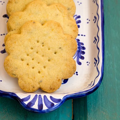 Lemon thyme flower shaped shortbread cookies on blue and white vintage decorative rectangular plate