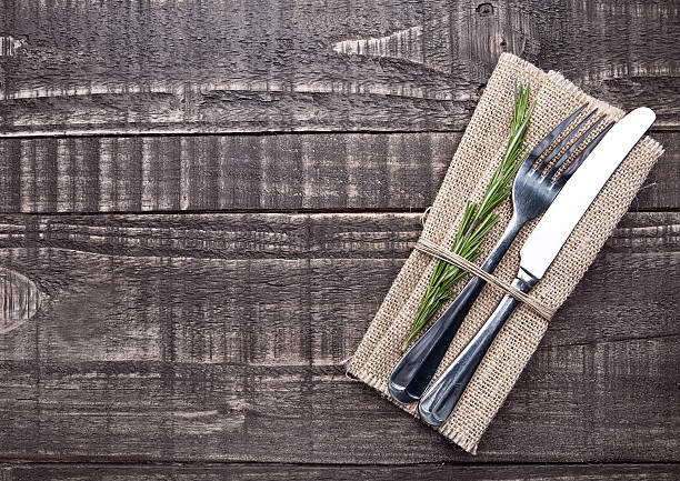 istock Knife and fork inside kitchen towel on wooden board 609092696