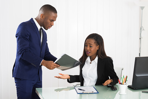 Unhappy Young Boss Showing Document To Her Female Worker In Office