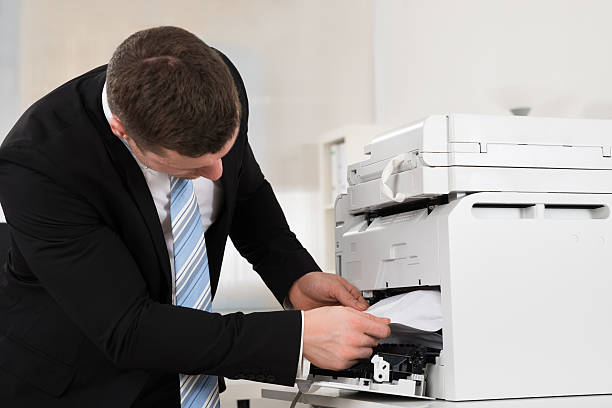istock Businessman Removing Paper Stuck In Printer 609094268