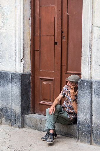 Havana, Cuba  - March 25, 2016: Old man smoking a cuban cigar outside an entrance