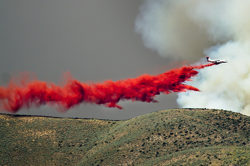 White Aircraft Dropping Fire Retardant as it Battles the Raging Wildfire