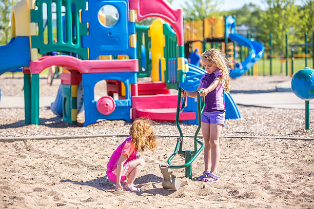 istock Two Young Girls Playing With Sand Digger at Playground 609097278