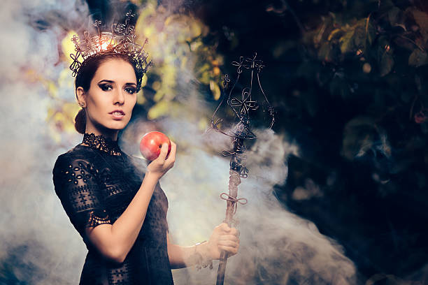istock Evil Queen with Poisoned  Apple in Misty Forest 609431580
