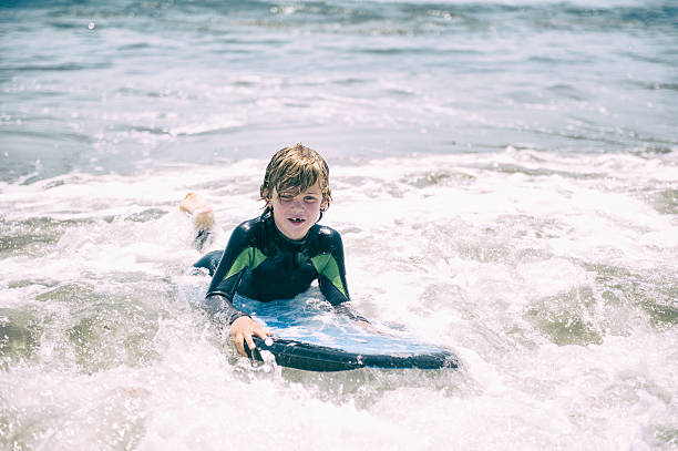 istock Young boy boogie boarding in the ocean 609440740