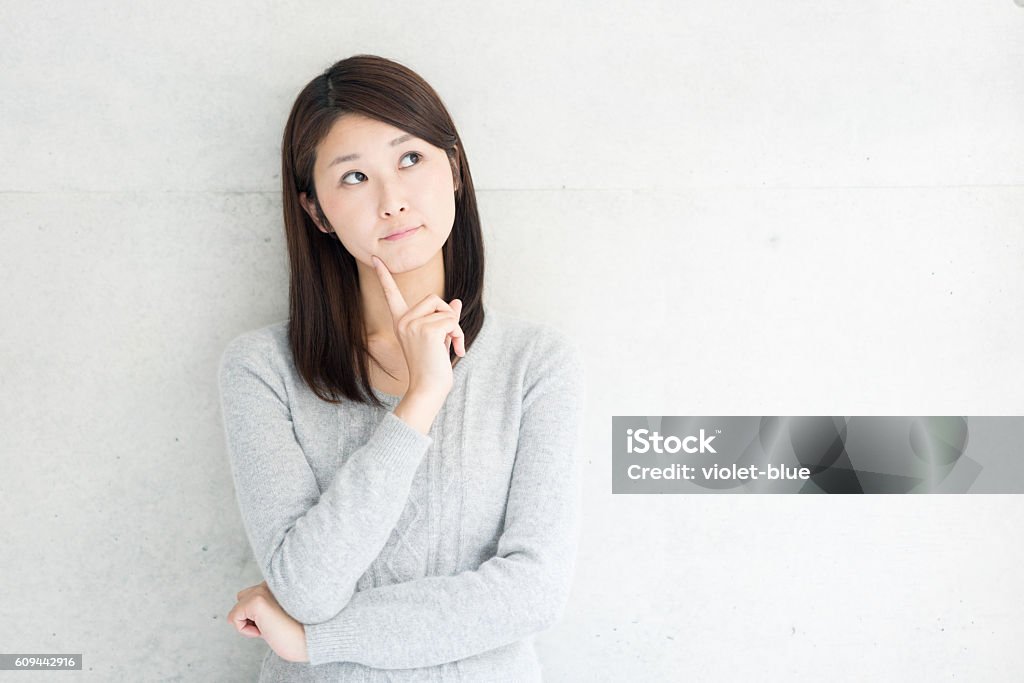 Thinking young woman Asian young woman thinking against concrete wall Question Mark Stock Photo