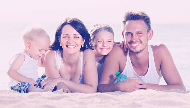 istock couple with two children lying on beach 609443282