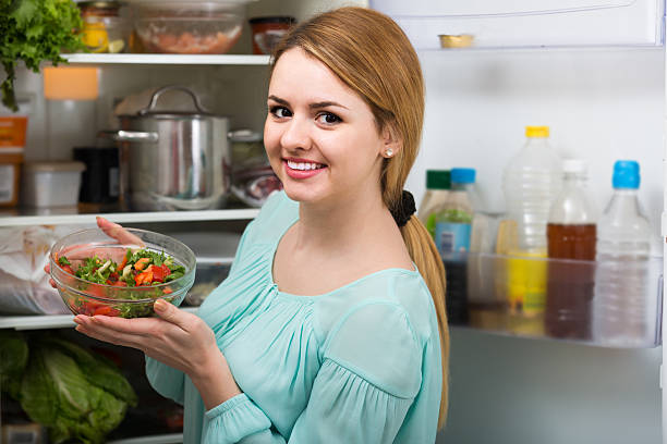 istock long-haired woman arranging space in fridge at home 609532520